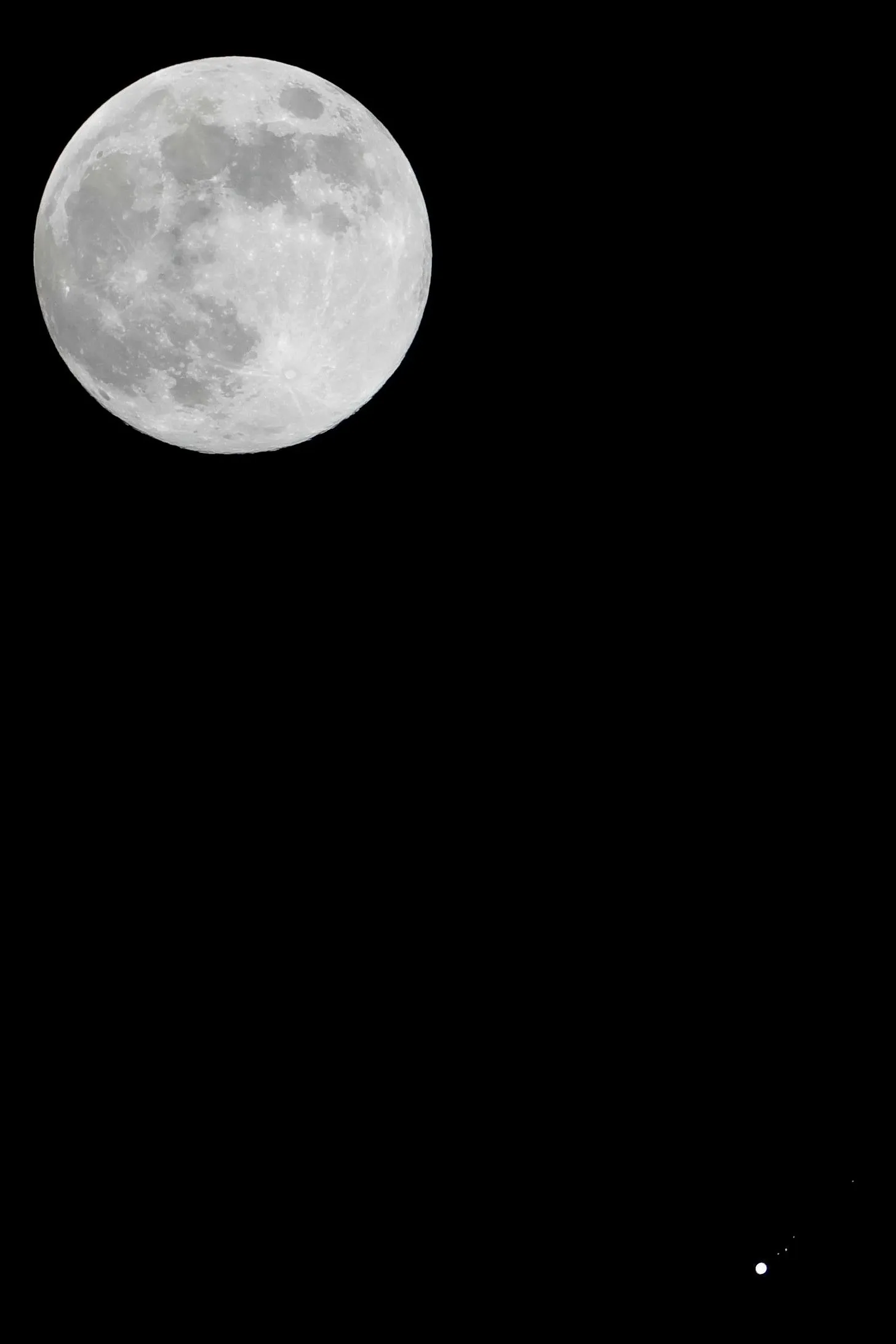 A full moon in the top-left with a relatively tiny Jupiter visible with a few of its moons