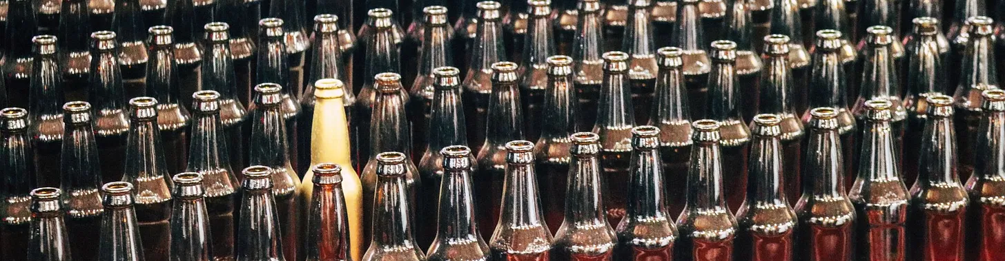 A collection of nicely arranged bottles with the same shape and contents, except one that stands out